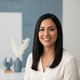 Portrait of a smiling Latina woman with sleek, shiny dark hair, looking confident and happy.